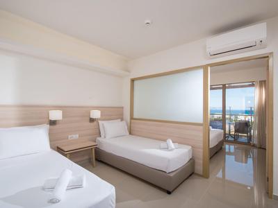 Camera d'hotel moderna con due letti singoli, mobili in legno e aria condizionata.