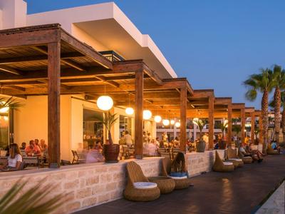 Außenbereich eines Hotels mit überdachten Sitzplätzen und Beleuchtung bei Sonnenuntergang.