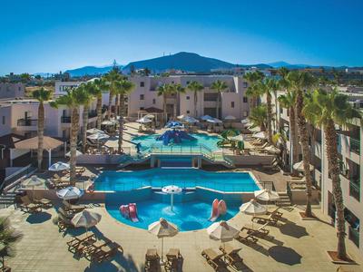 Duży kompleks hotelowy z kilkoma basenami, palmami i leżakami pod czystym niebem.