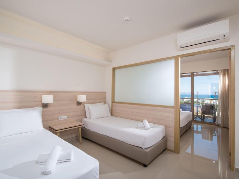 Camera d'hotel moderna con due letti singoli, mobili in legno e aria condizionata.