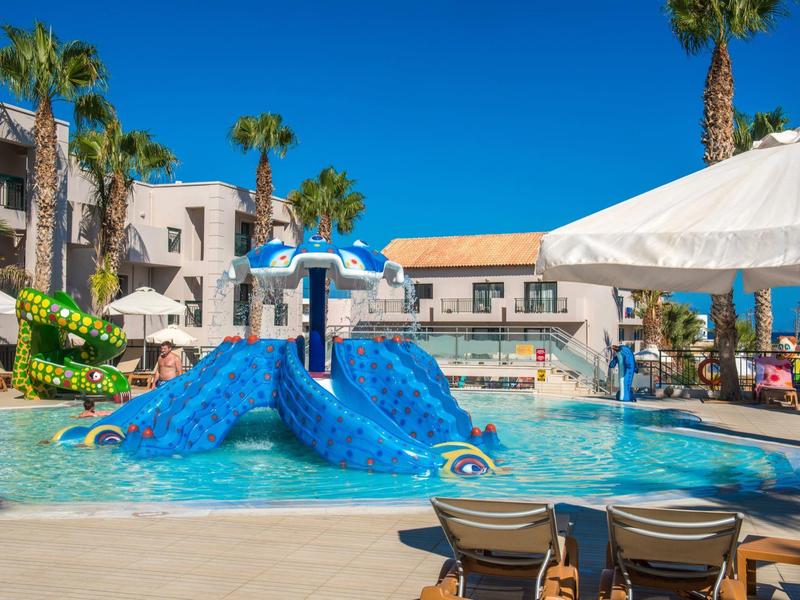 Piscina dell'hotel con struttura giochi d'acqua colorata circondata da sdraio e ombrelloni sotto un cielo blu
