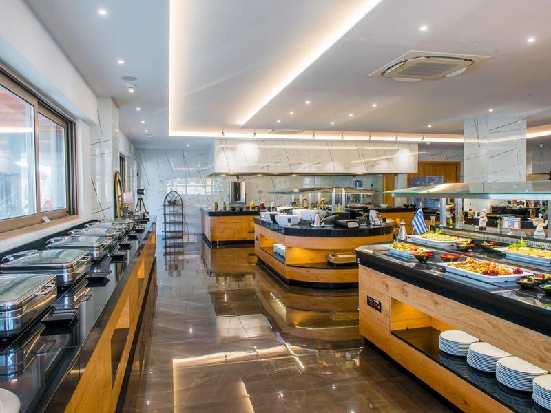 Sala da pranzo moderna dell'hotel con stazioni buffet e abbondante luce naturale dalle grandi finestre.