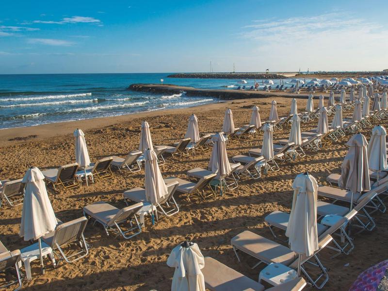 Spiaggia di sabbia vuota con file di ombrelloni chiusi e sdraio con tempo sereno