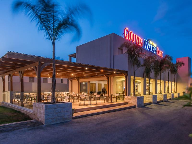 Hotel moderno al tramonto con insegna illuminata e area esterna con posti a sedere