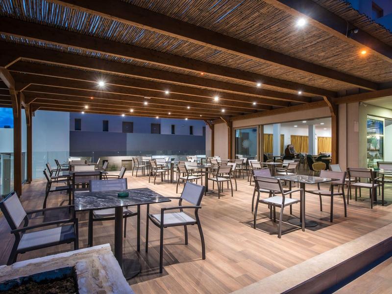 Terrazza coperta con più tavoli e sedie al crepuscolo in un hotel