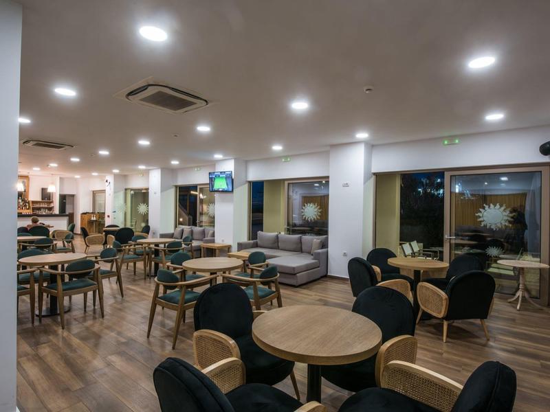 Sala da pranzo moderna con pavimento in legno, tavoli rotondi e sedie comode in un hotel.