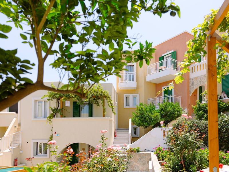 Vue extérieure d'un hôtel coloré avec balcons et végétation luxuriante.