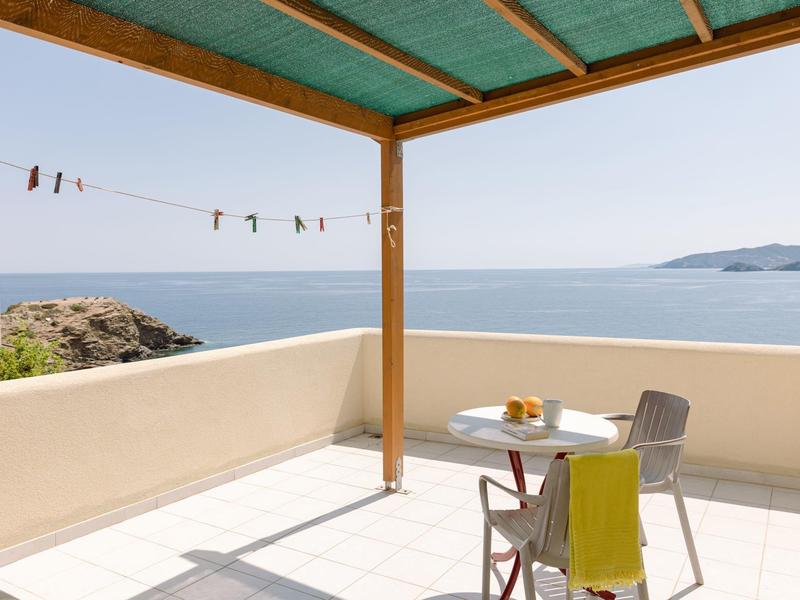 Terrasse avec table et chaise sous un auvent vert avec vue sur la mer