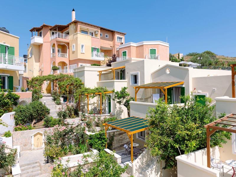 Hôtel rose à plusieurs étages avec terrasses blanches et verdure luxuriante sous un ciel bleu clair.