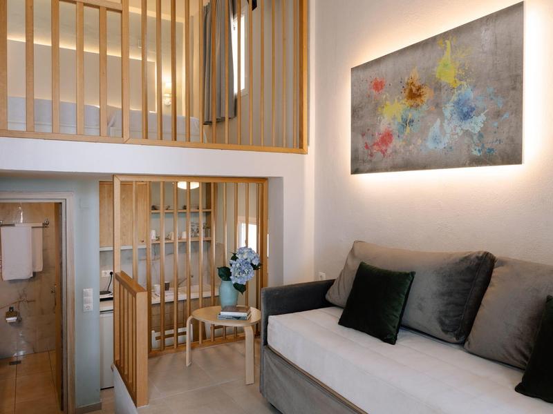 Espace de vie moderne avec canapé, escalier en bois, table à manger et art mural abstrait.