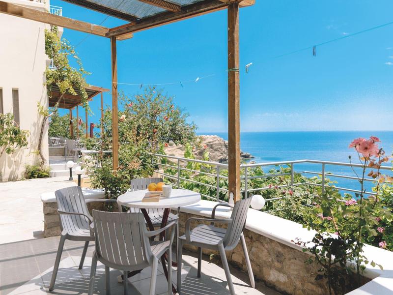 Terrasse avec table dressée et vue sur la mer sous un ciel clair