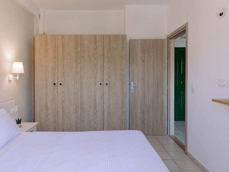 Chambre d'hôtel moderne avec lit, armoire et salle de bain ouverte.