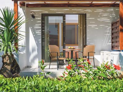 Patio con tavolo e sedie davanti a una casa, circondato da piante e ombre