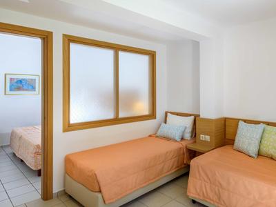 Camera d'hotel accogliente con due letti singoli, pareti chiare e finestra con cornice in legno.