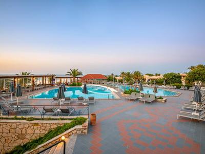 Area piscina moderna con lettini e palme al tramonto.