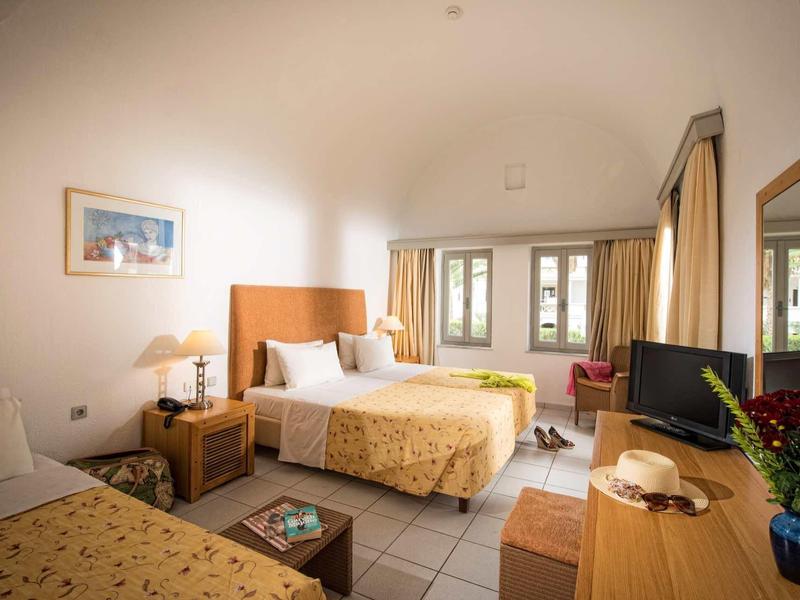 Camera d'hotel luminosa con letto matrimoniale, finestra, scrivania e zona salotto.