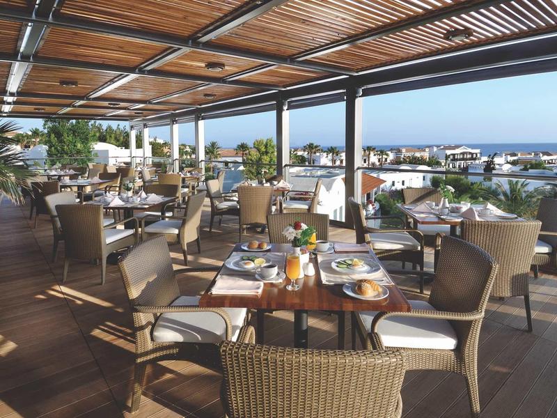 Terrazza aperta con tavoli apparecchiati e vista mare in un ristorante dell'hotel.