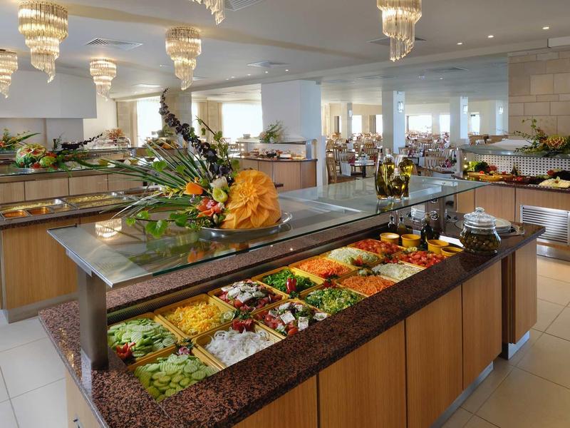 Buffet con insalate e piatti freschi in un ristorante luminoso con grandi finestre.