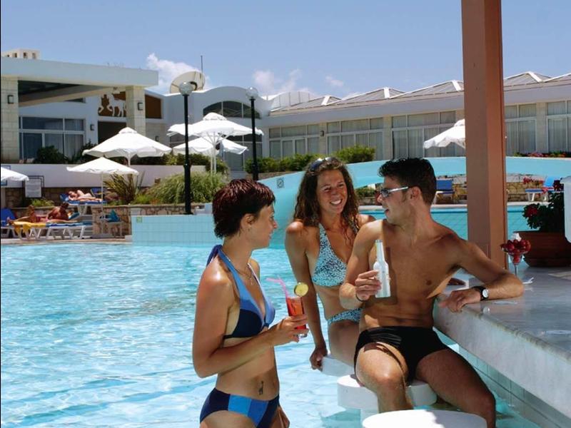 Tre persone si rilassano al bar in piscina di un hotel in una giornata di sole.