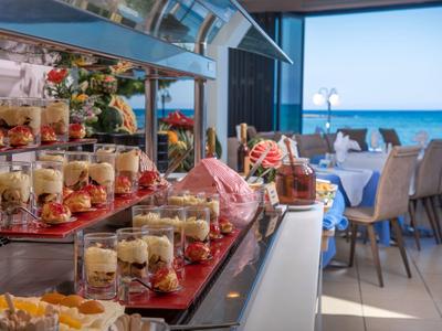 Buffet mit Dessertgläsern und Sitzbereich mit Meerblick in einem Hotelrestaurant