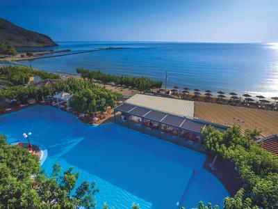 Großer Pool mit Blick auf das Meer und eine Strandpromenade mit Sonnenschirmen.