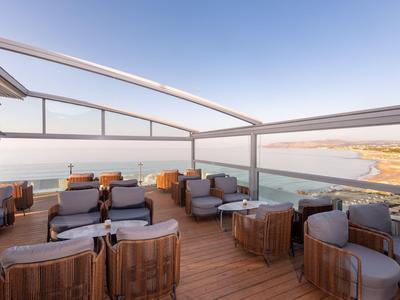 Terrazza sul tetto con comodi gruppi di sedute e vista sul mare in una giornata limpida.