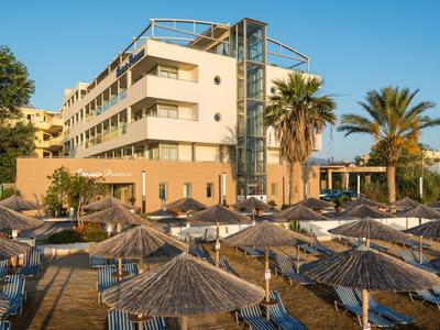 Complesso alberghiero moderno con ombrelloni e palme su una spiaggia soleggiata.