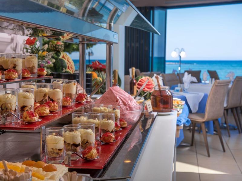 Buffet mit Dessertgläsern und Sitzbereich mit Meerblick in einem Hotelrestaurant