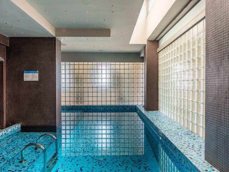 Modernes Hallenbad mit Glasbausteinwänden und Mosaikfliesen im Hotel.