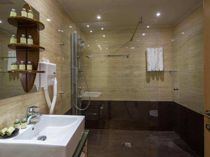 Modernes Badezimmer mit Dusche, Waschbecken und Wandregal mit Pflegeprodukten.