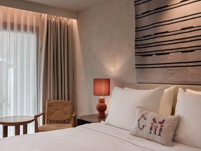 Chambre d'hôtel confortable avec lit grand, lampe de chevet et coin salon près de la fenêtre.