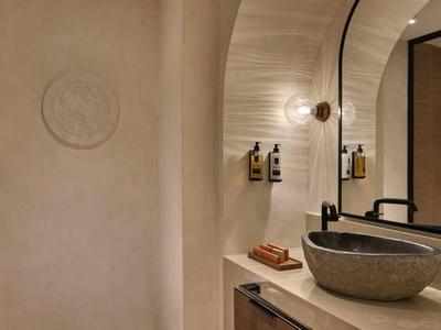 Salle de bain moderne avec lavabo rond en pierre naturelle et miroir rond décoratif.