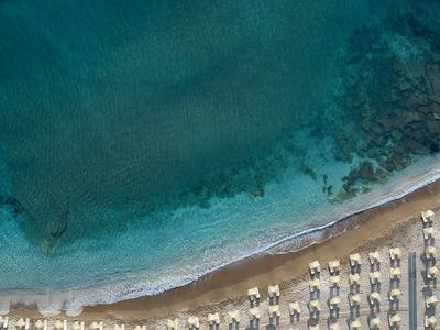 Strand mit Reihen von Liegestühlen und Schirmen neben klarem blauem Wasser