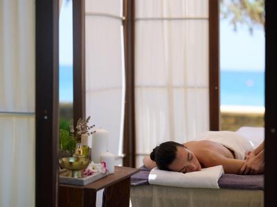 Frau erhält Massage auf einer Liege mit Blick aufs Meer durch Fenster.