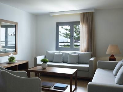 Modern eingerichtetes Wohnzimmer mit grauen Sofas, Holztisch und Fenster mit Blick nach draußen.