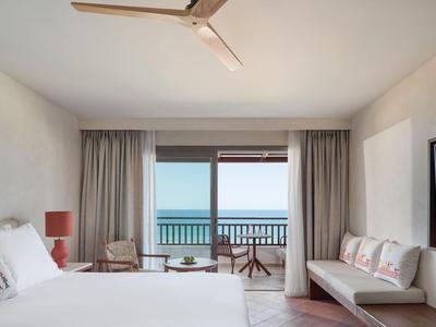 Modernes Hotelzimmer mit Bett, Sofa, Balkon und Meerblick.