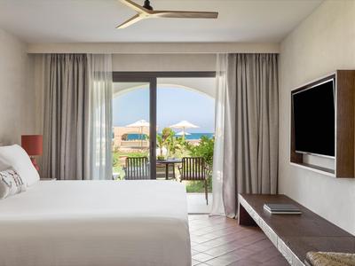 Modernes Hotelzimmer mit großem Bett und Blick auf Balkon und Berge im Hintergrund.