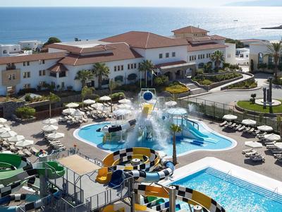 Hotel con piscina all'aperto, scivoli d'acqua e ombrelloni vicino al mare.