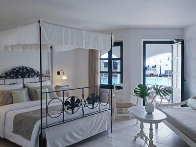 Chambre d'hôtel lumineuse avec deux lits, coin salon confortable et vue sur une terrasse.