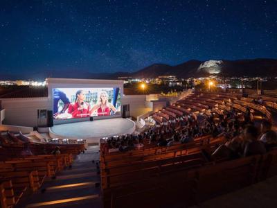 Cinema all'aperto notturno con pubblico e cielo stellato limpido.