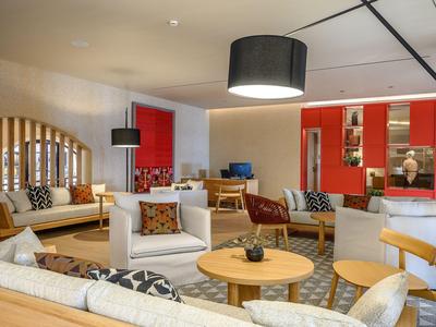 Modern eingerichteter Hotel-Loungebereich mit Sofas, Sesseln und runden Holztischen.