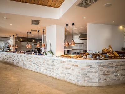 Espace buffet moderne avec revêtement en pierre et lampes suspendues dans une pièce lumineuse.