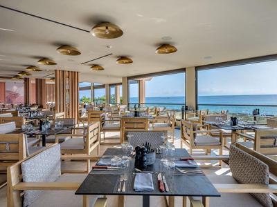 Helles Restaurant mit Holzmöbeln und Meerblick durch große Fenster