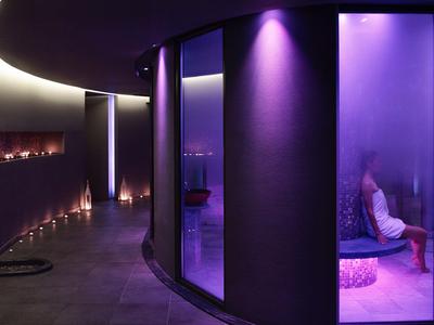 Moderne Hotellounge mit sanfter, violetter Beleuchtung und geschwungenen Wänden