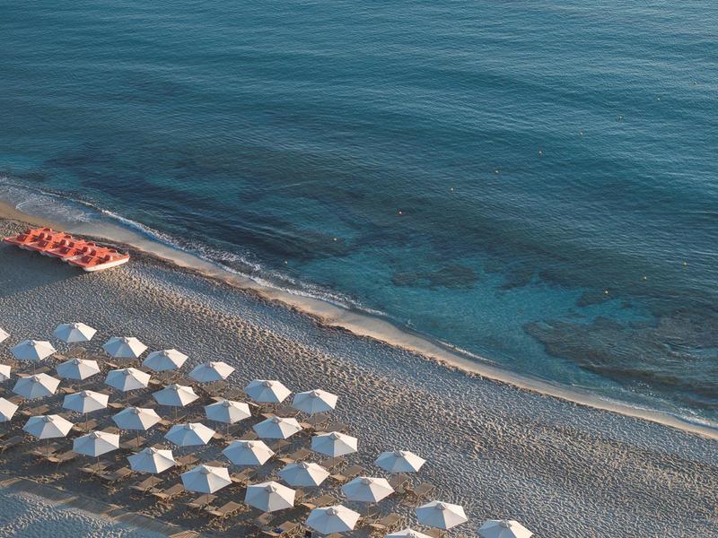Plage avec parasols blancs et mer bleue calme en arrière-plan
