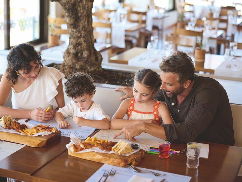 Famille mangeant ensemble dans un restaurant lumineux avec des tables en bois.
