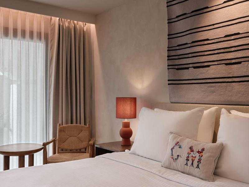 Chambre d'hôtel confortable avec lit grand, lampe de chevet et coin salon près de la fenêtre.