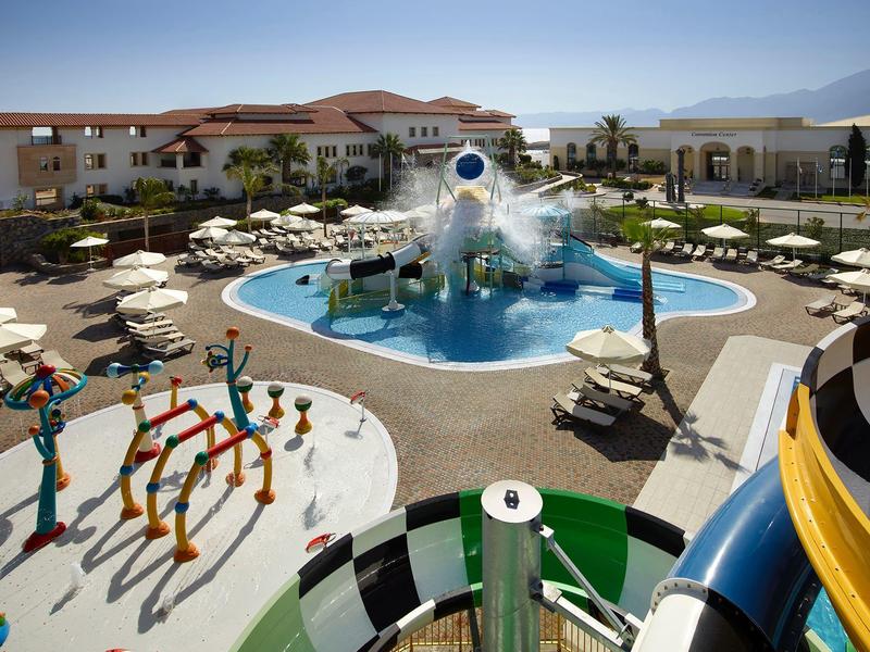 Hôtel avec piscine extérieure, toboggans aquatiques et aire de jeux pour enfants par temps ensoleillé.