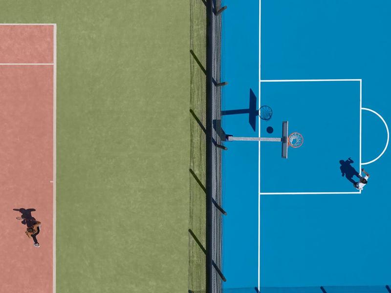 Vue aérienne d'un court de tennis coloré avec trois joueurs par temps ensoleillé.