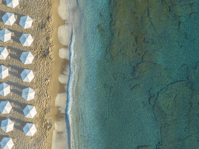 Vue aérienne d'une plage avec des parasols blancs et une eau bleu clair